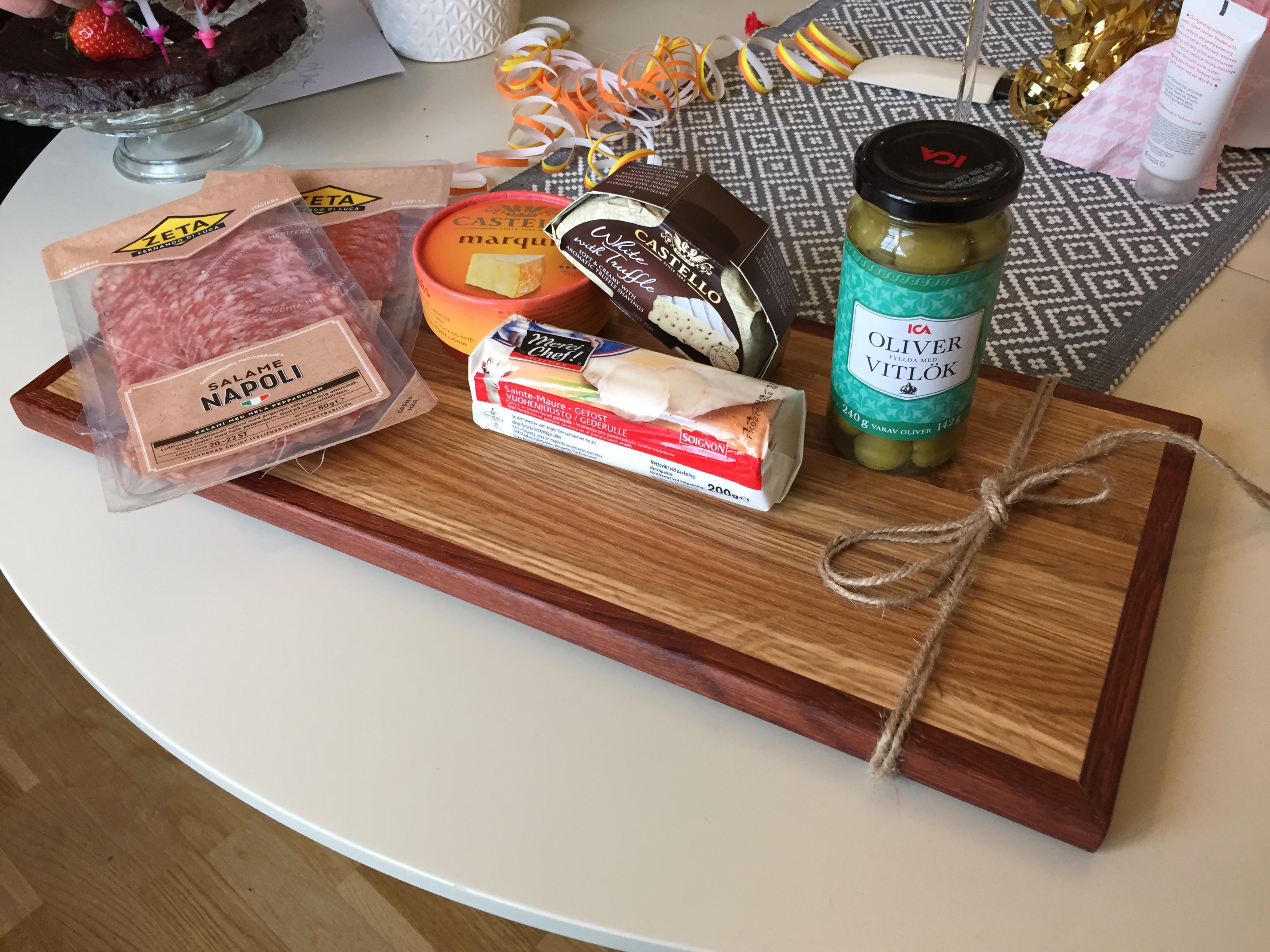 Skärbräda i ek som är inslagen till present med tillbehör för en ostbricka på